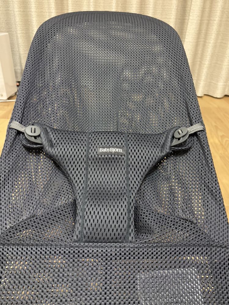 バウンサーのシート上部。BabyBjörnのタグと、左右のストラップ調整パーツ