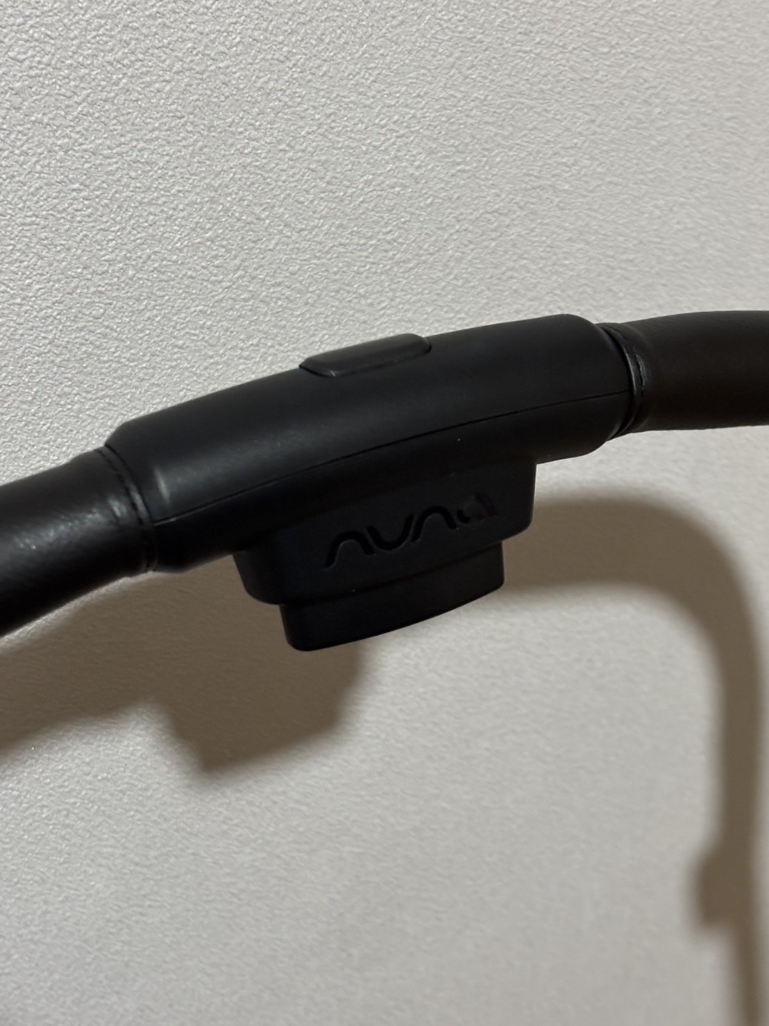 NUNA IXXA swivのハンドル中央にあるボタンと、その下のnunaロゴ入りの取付部